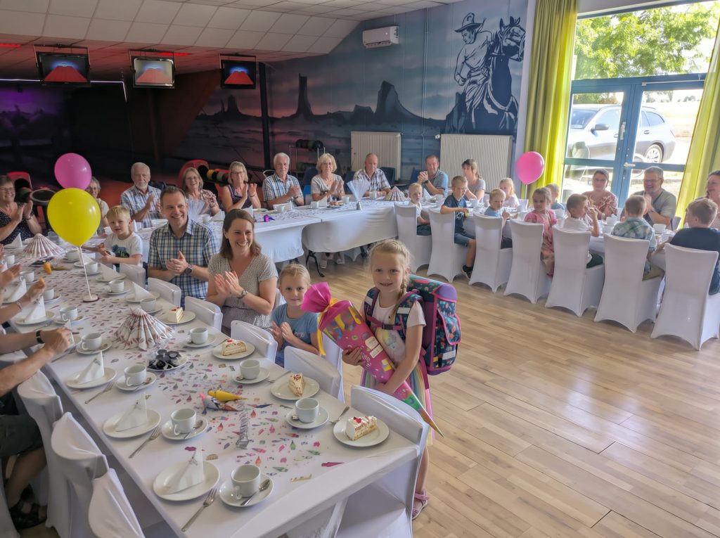 Schuleinführung im Freizeitpark Landsberg: Kind mit Zuckertüte vor voll besetzter Kaffeetafel mit Familie und Gästen