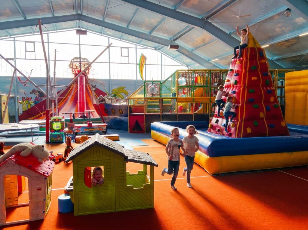 Kinder klettern auf die Kletterpyramide und rennen durch das Kinderparadies